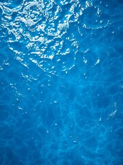 Azure expanse unfolds, a liquid sapphire canvas kissed by sun, revealing intricate water textures from an aerial perspective,  texture,  reflections