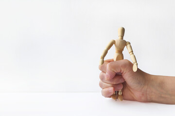 A wooden mannequin, held in a hand and demonstrating a grasping motion, is depicted against a white...