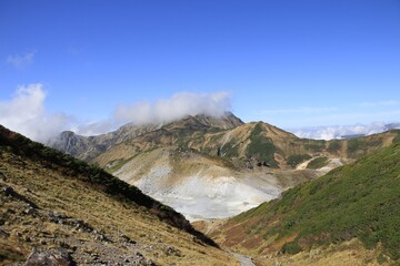 Fototapeta premium Vast Alpine Valley with Steam Vents and Rolling Mountain Ridges
