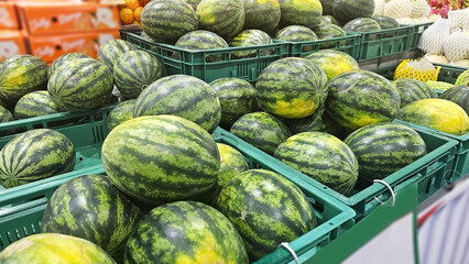 Watermelons on Display: A vibrant display of ripe watermelons, neatly arranged in crates, creates a...