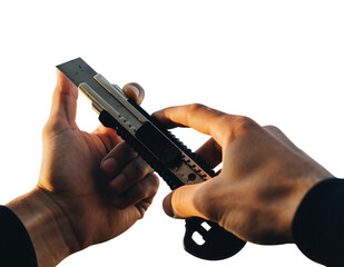 Human hands, illuminated by warm light, carefully adjust a sharp metallic blade on a black and silver utility knife,, isolated on white background