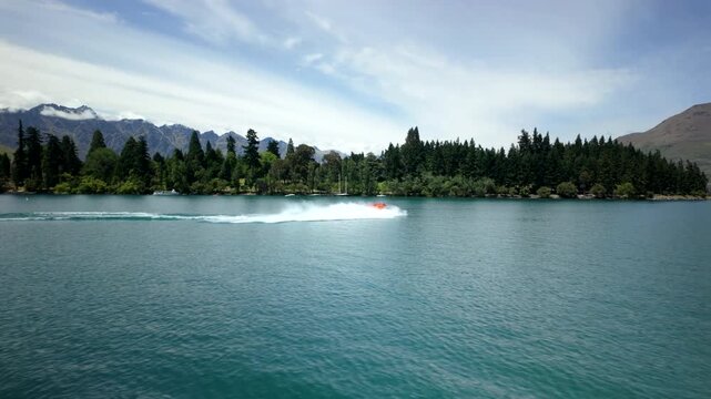 Speedboat on turquoise lake with mountain backdrop and forest shore