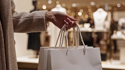 Woman holding white shopping bags in a clothing store.