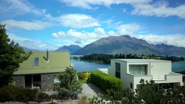 Window view of lakeside homes and mountains under blue sky