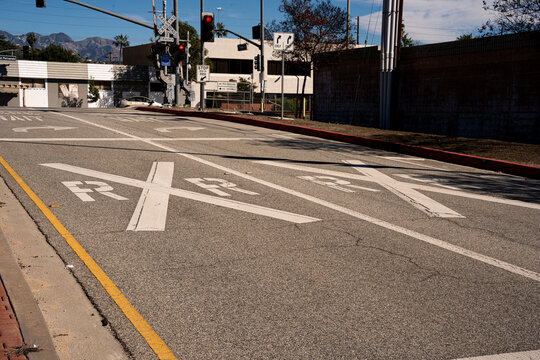 Railroad crossing markings on asphalt road with traffic signals and buildings in background