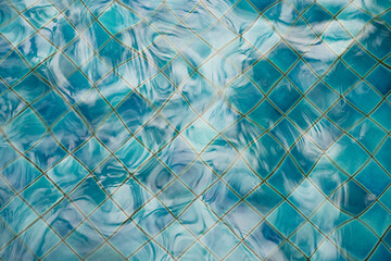 Top view of clear blue swimming pool water surface with ripples and waves reflecting sunlight....