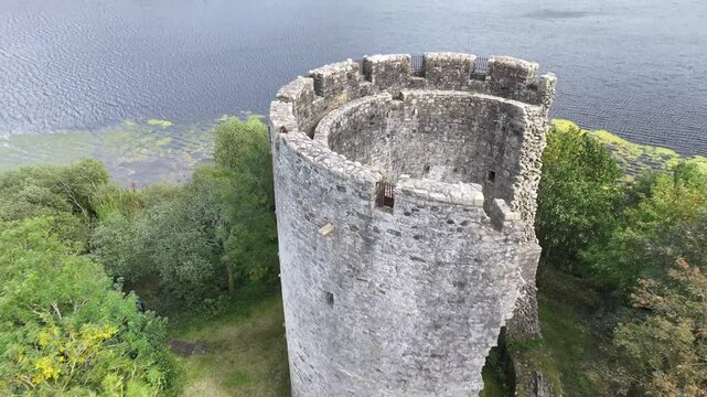Dynamic drone reveal over castle tower on island on lake. Historical building in Ireland, Europe