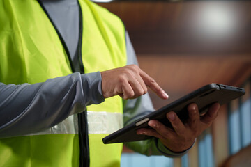 A professional construction engineer or site supervisor stands confidently in a modern wooden...