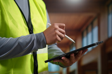 A professional construction engineer or site supervisor stands confidently in a modern wooden...