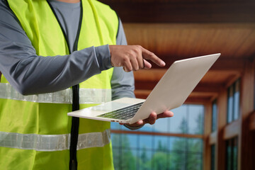 A professional construction engineer or site supervisor stands confidently in a modern wooden...