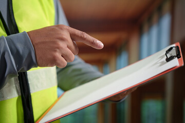 A professional construction engineer or site supervisor stands confidently in a modern wooden...