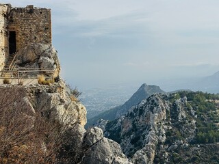 St. Hilarion Castle rising high in the Kyrenia Mountains with the distant coastal city of Kyrenia visible below, featuring dramatic cliffs, medieval stone walls, and sweeping views of northern Cyprus