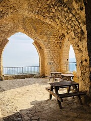 One of the interior halls of St. Hilarion Castle with elegant arched windows opening to sweeping views of the northern coastline of Cyprus, showcasing medieval stone architecture, soft natural light