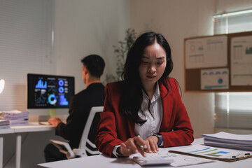 Stressed businesswoman calculating finances during late night work