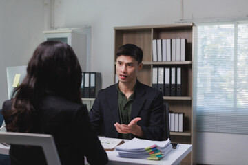 Employee having a discussion with colleague at office desk