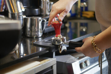 Barista prepares coffee using a tamper at coffee shop