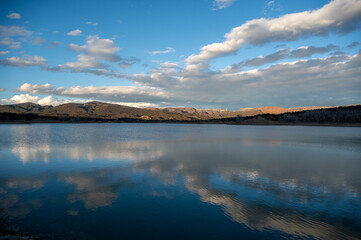 Colorful sunset cloudscape over Grass Valley Reservoir in Harvey Gap State Park, Colorado reflected in lake's calm water.