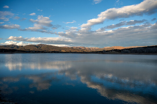 Colorful sunset cloudscape over Grass Valley Reservoir in Harvey Gap State Park, Colorado reflected in lake's calm water.