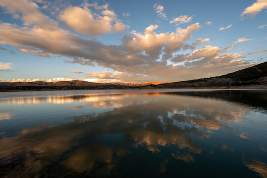 Colorful sunset cloudscape over Grass Valley Reservoir in Harvey Gap State Park, Colorado reflected in lake's calm water.