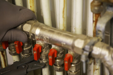 Technician Adjusting Valves in Industrial Pipeline with Gloved Hand for Maintenance