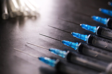 Close-Up of Line of Empty Syringes on a Metallic Surface with Blue Caps