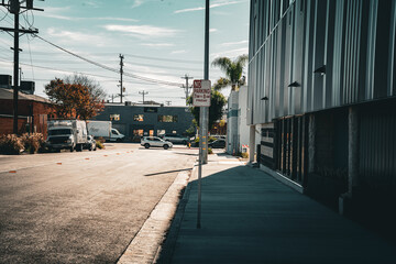 Obraz premium Sunny urban street scene with modern building and parked vehicles