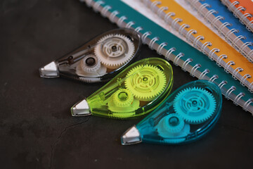 Colorful Correction Tape and Spiral Notebooks on Dark Background: Stationery Essentials for Creative Workspaces