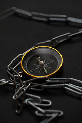 Compass Surrounded by Chain on Dark Surface: Navigating Challenges and Constraints in Business Concept