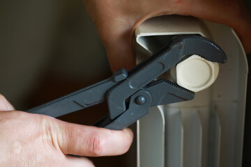 Hands Adjusting Radiator Valve with Wrench: Home Maintenance and Heating Efficiency Concept