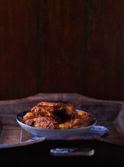 Fried chicken wings with potatoes on a rustic background. Soft focus.
