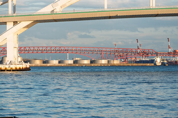 夢舞大橋越しに望む港大橋の赤いトラスと桜島埠頭の石油タンク群（大阪港・工業地帯の風景）
