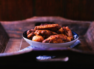 Fried chicken wings with potatoes on a rustic background. Soft focus.
