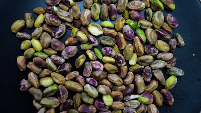 Close-up of unshelled pistachios on a dark surface