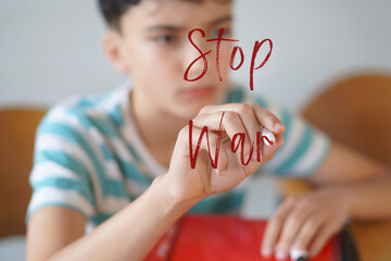 stop war. Preteen boy writing text on the screen with a red marker
