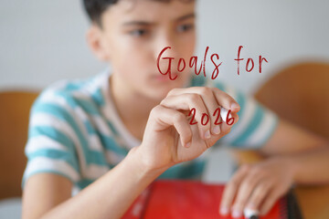 goals for 2026. Preteen boy writing text on the screen with a red marker
