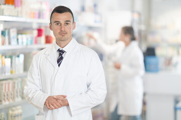 Young male pharmacist worker in uniform posing in pharmacy