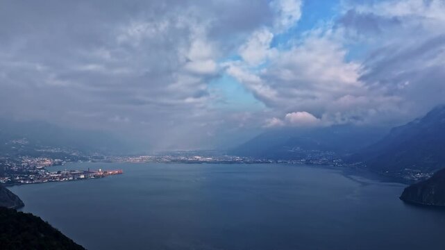 Ethereal mist and clouds hover above Lago d&rsquo;Iseo, blue dusk tones across forested hills and open water