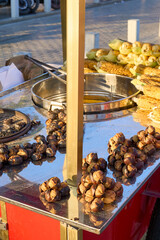 A street vendor sells roasted chestnuts and corn on the cob, a popular snack.