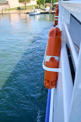 View from a boat with an orange life preserver, the water, and a shoreline in the background.