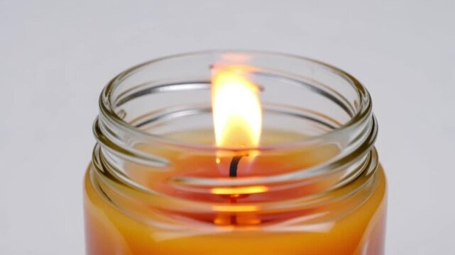 Candle flame flickering in glass jar, isolated white background