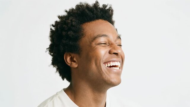 Joyful young man smiling with curly hair against a simple white background