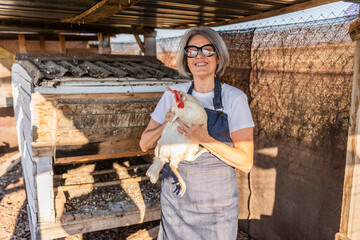 Woman holding free range chicken near coop