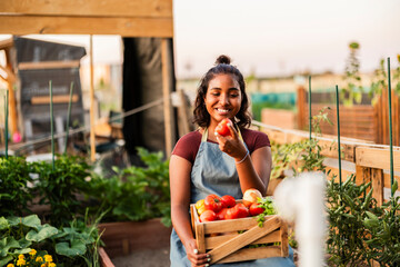 Happy woman holding fresh organic tomatoes from urban garden
