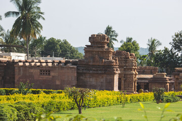 Ancient temple complex in India surrounded by green gardens and palm trees under bright sunlight