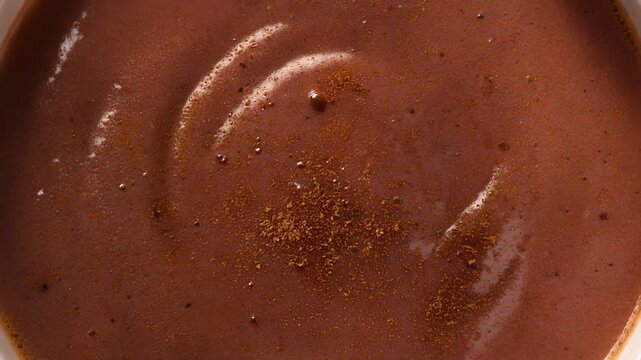 Rich creamy hot chocolate texture with a beautiful swirl pattern and sprinkled cocoa powder detail