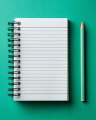 Blank spiral notebook with lined paper and a mint green pencil on a vibrant teal background, top view flat lay.