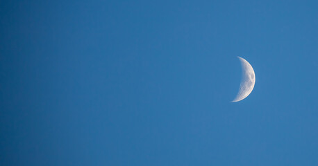 New moon in a blue sky. Crescent moon. Close-up of the moon in the evening or night sky.