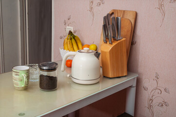 Kitchen counter with kettle, fruit, tea, and knife block, ready for morning preparations