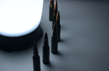 Camping Lamp Illuminates Bullets Lined Up in a Semicircle on a White Surface