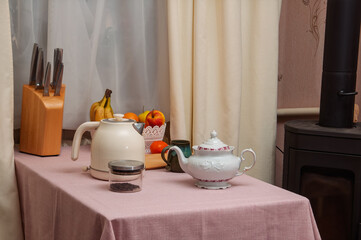 Cozy kitchen scene with tea set, fruit, and knives on a pink tablecloth